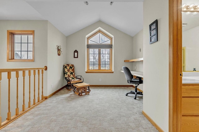 carpeted office space with built in desk and vaulted ceiling