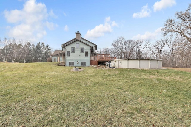 rear view of property featuring a yard and a pool side deck