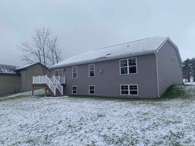 snow covered back of property with a deck