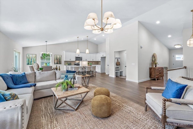 living room featuring plenty of natural light, dark wood-type flooring, high vaulted ceiling, and an inviting chandelier