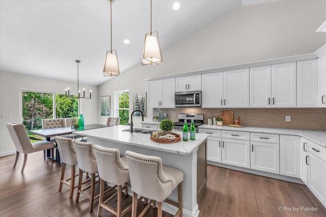 kitchen featuring sink, decorative light fixtures, a center island with sink, white cabinets, and appliances with stainless steel finishes