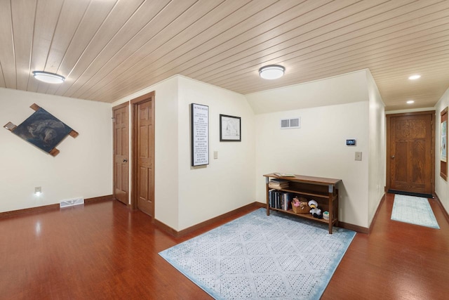 hallway with dark hardwood / wood-style floors, vaulted ceiling, and wooden ceiling