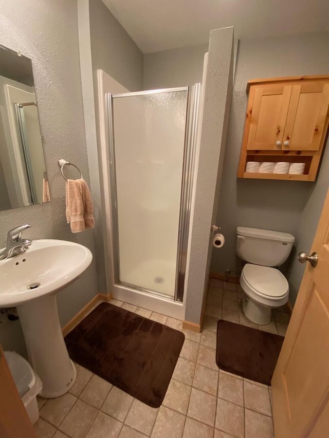 bathroom featuring toilet, tile patterned floors, and a shower with door