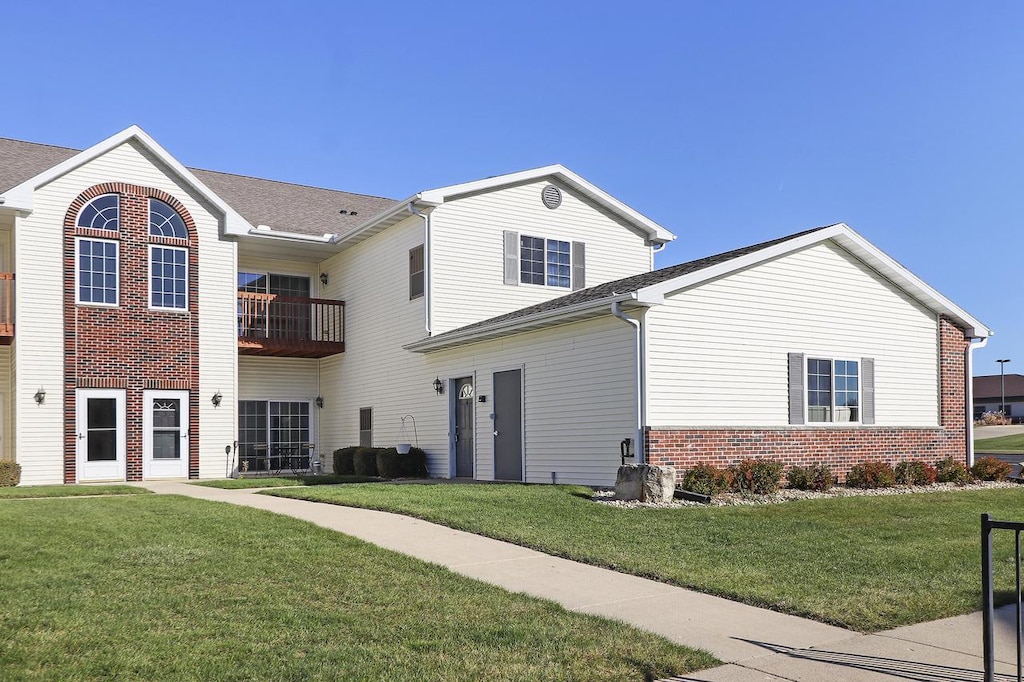 view of front of property featuring a balcony and a front yard