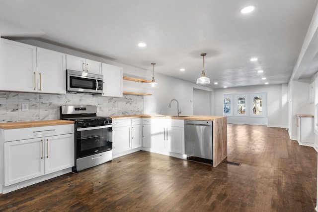 kitchen featuring kitchen peninsula, white cabinetry, stainless steel appliances, and hanging light fixtures