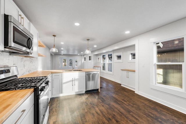 kitchen with decorative light fixtures, white cabinetry, appliances with stainless steel finishes, and wooden counters