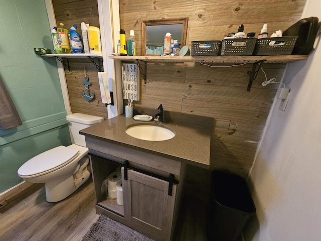 bathroom with vanity, toilet, wood-type flooring, and wooden walls