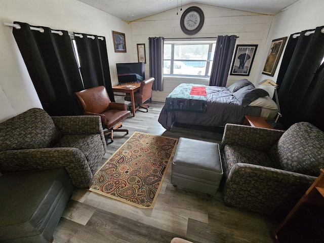 bedroom with wood-type flooring, a textured ceiling, and vaulted ceiling