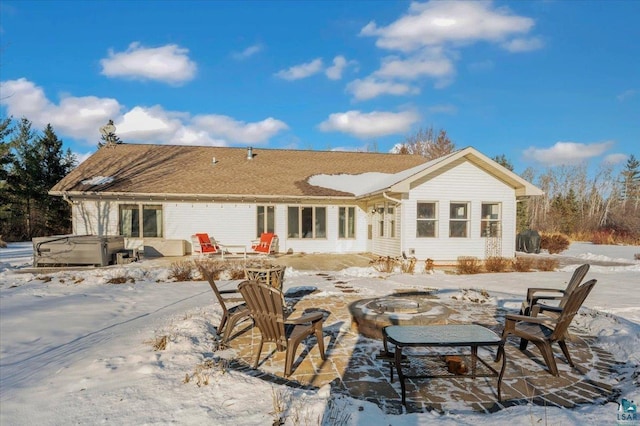 snow covered house with a patio area, a hot tub, and a fire pit