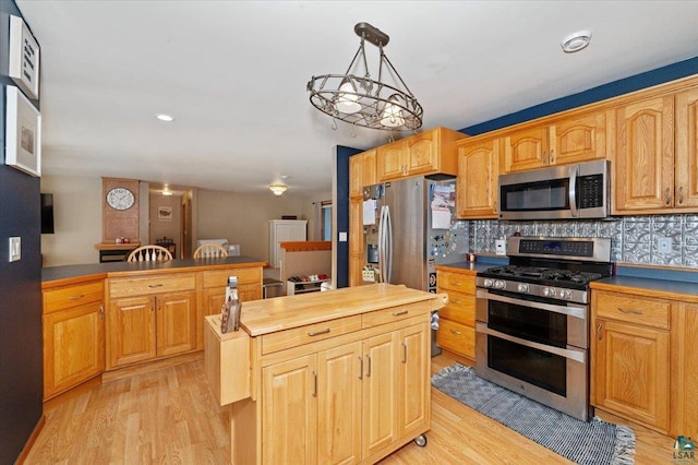 kitchen with decorative light fixtures, tasteful backsplash, stainless steel appliances, and light hardwood / wood-style flooring