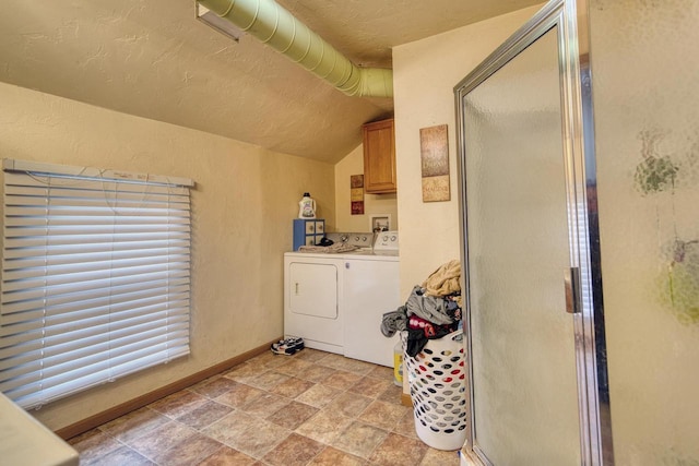 clothes washing area featuring washing machine and dryer, cabinets, and a textured ceiling