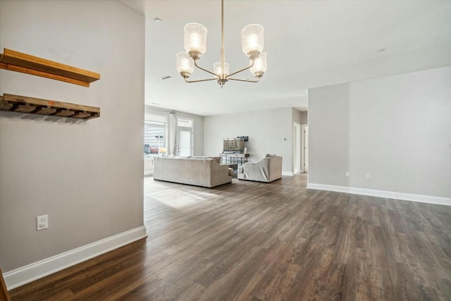 unfurnished living room featuring dark wood-type flooring and a notable chandelier