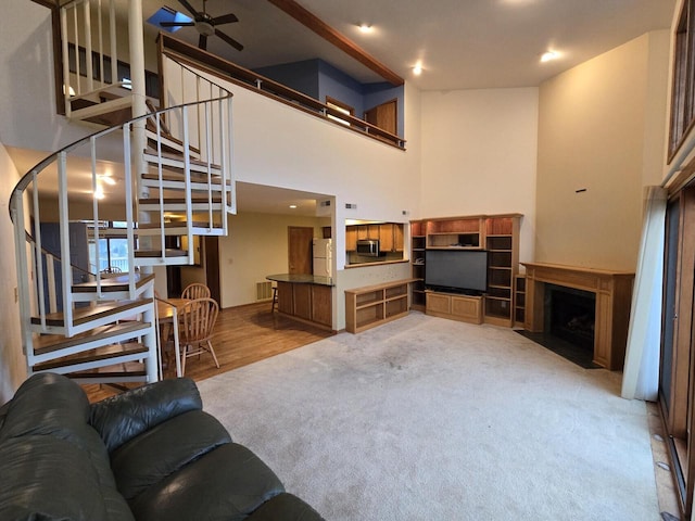 living room with ceiling fan, a high ceiling, and light wood-type flooring