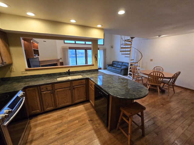 kitchen featuring electric range, light wood-type flooring, kitchen peninsula, and sink