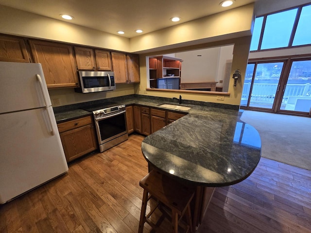 kitchen featuring sink, stainless steel appliances, kitchen peninsula, light hardwood / wood-style floors, and a kitchen bar