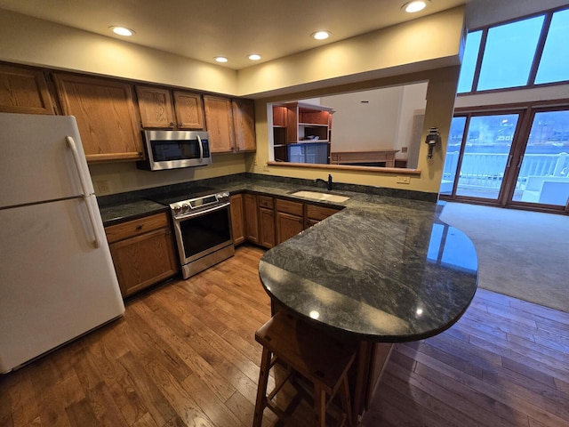 1470 S Delavan Club Dr Unit 6, Delavan, WI 53115 - kitchen with stainless steel appliances, recessed lighting, brown cabinetry, a peninsula, and wood finished floors