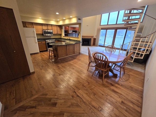 dining space with light hardwood / wood-style floors, sink, and a high ceiling