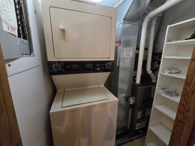 clothes washing area with electric panel and stacked washer and clothes dryer