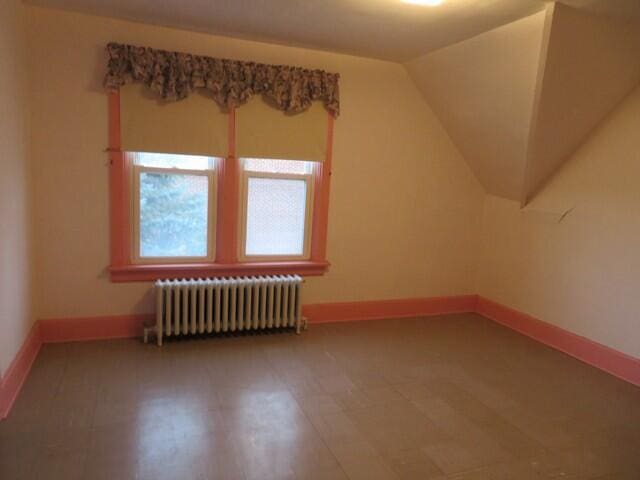 additional living space featuring radiator heating unit and lofted ceiling