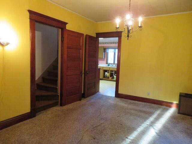 unfurnished room featuring carpet, ornamental molding, and a chandelier