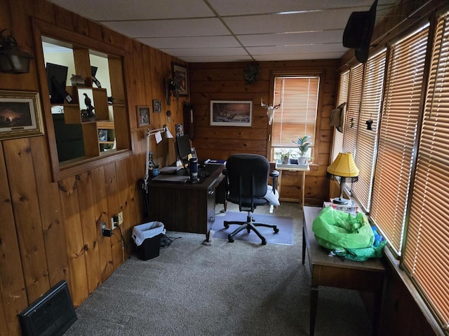 carpeted home office featuring a drop ceiling and wood walls