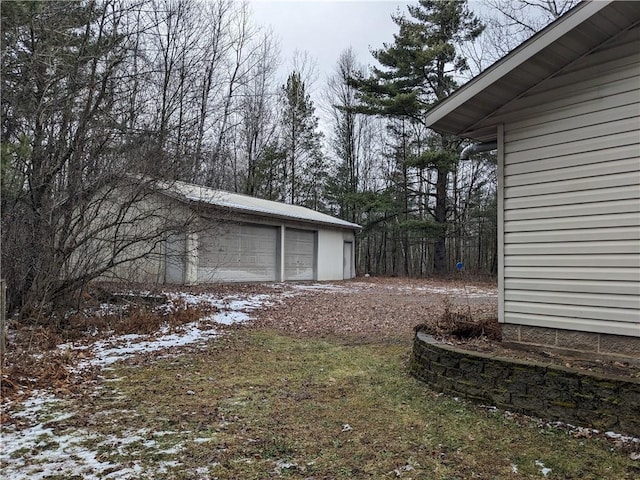 yard layered in snow featuring a garage and an outdoor structure