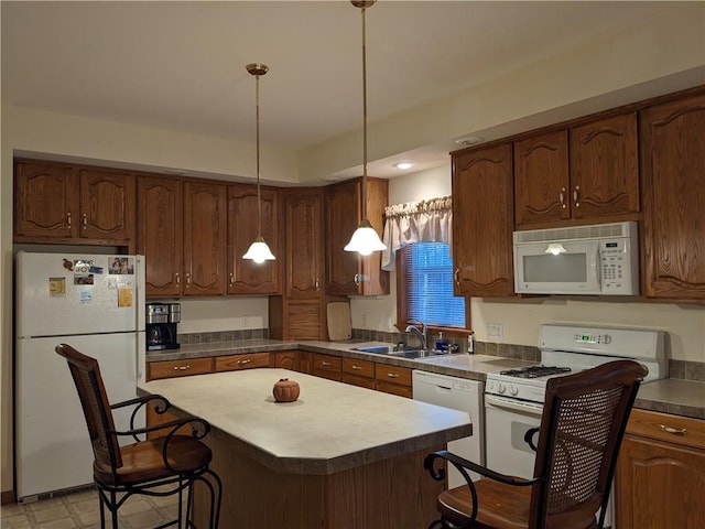 kitchen with pendant lighting, a breakfast bar, white appliances, sink, and a kitchen island