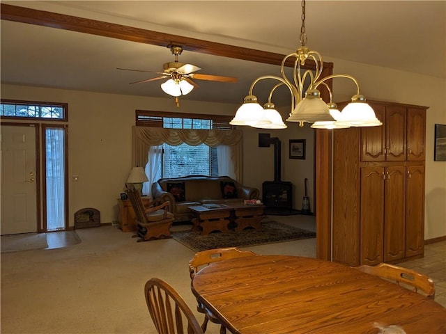 carpeted dining room featuring ceiling fan with notable chandelier and a wood stove