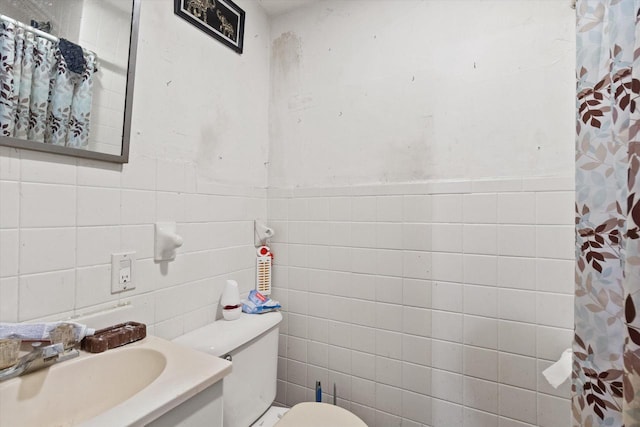 bathroom with walk in shower, vanity, toilet, and tile walls