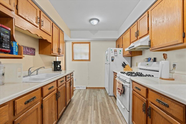 kitchen featuring white appliances, sink, and light hardwood / wood-style flooring