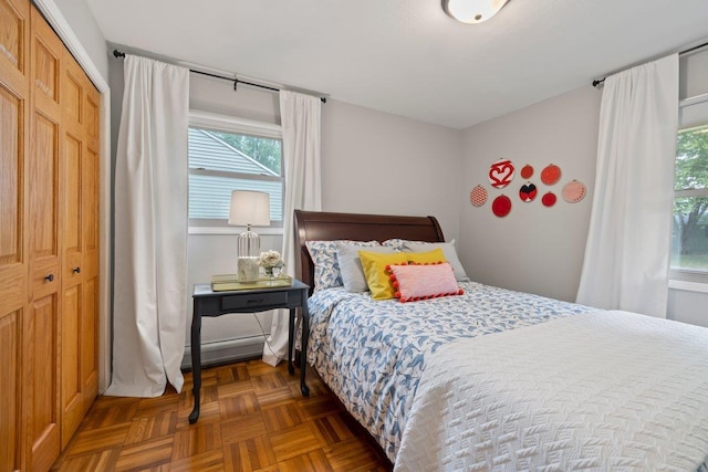 bedroom featuring multiple windows, a closet, and dark parquet flooring