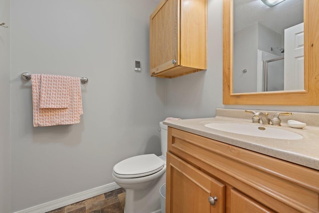 bathroom featuring vanity, toilet, and a shower with door