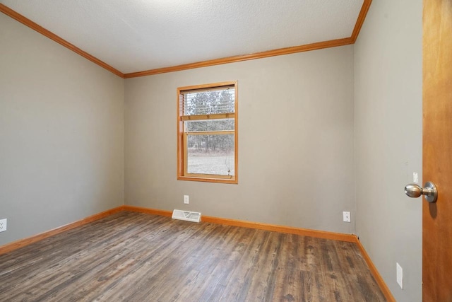 spare room with a textured ceiling, ornamental molding, and dark wood-type flooring