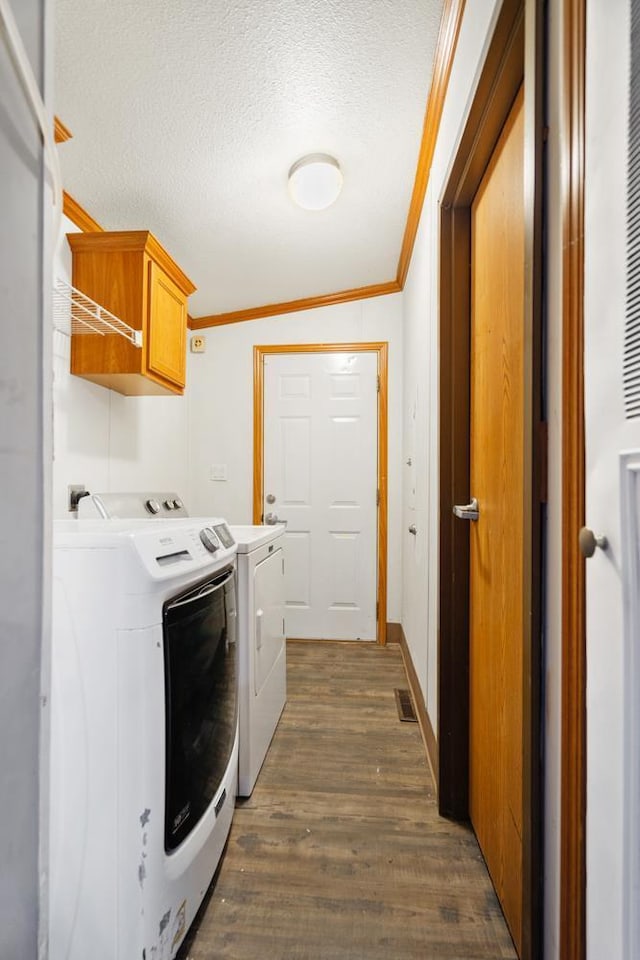 laundry room featuring cabinets, ornamental molding, dark wood-type flooring, and washing machine and dryer