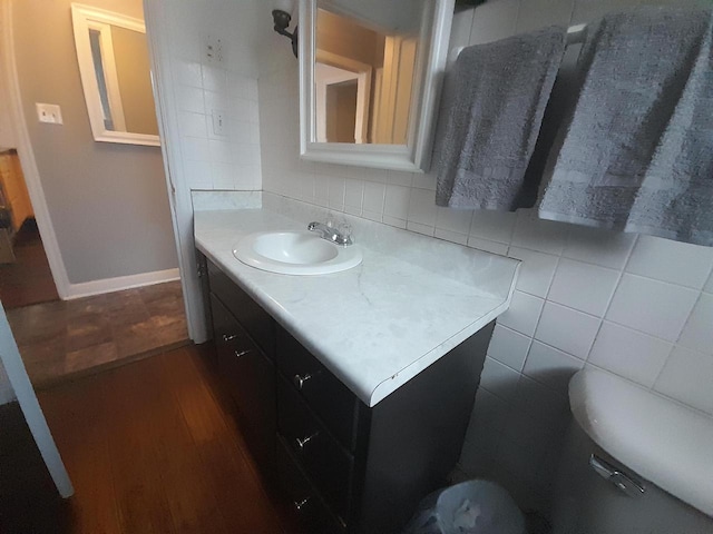 bathroom with vanity, hardwood / wood-style flooring, toilet, tile walls, and tasteful backsplash