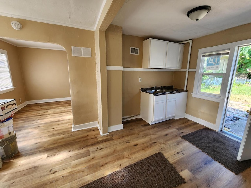 kitchen featuring white cabinets, light wood-type flooring, and sink