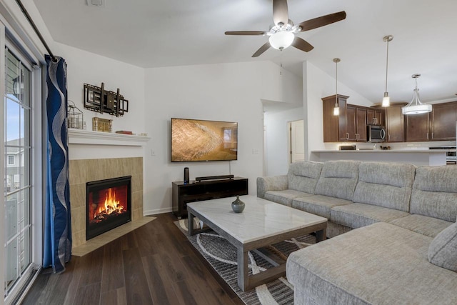 living room featuring a tiled fireplace, ceiling fan, dark wood-type flooring, and lofted ceiling