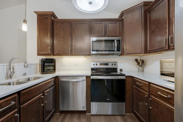 kitchen featuring sink, hanging light fixtures, lofted ceiling, dark brown cabinets, and appliances with stainless steel finishes