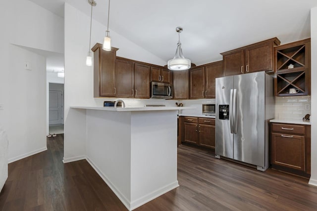 kitchen with pendant lighting, vaulted ceiling, appliances with stainless steel finishes, dark brown cabinets, and dark hardwood / wood-style flooring