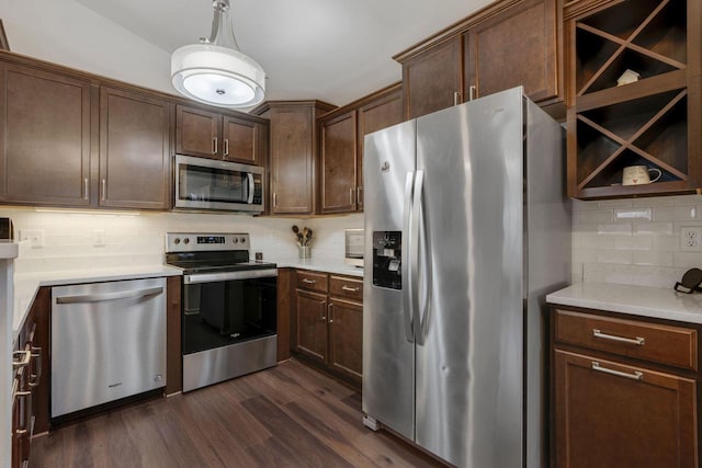 kitchen with dark brown cabinetry, dark wood-type flooring, pendant lighting, decorative backsplash, and appliances with stainless steel finishes