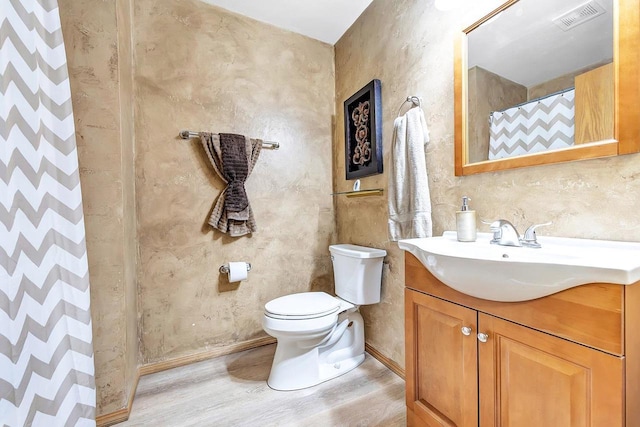 bathroom featuring vanity, toilet, wood-type flooring, and walk in shower