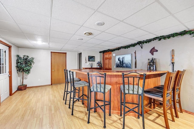 bar featuring a paneled ceiling and light wood-type flooring