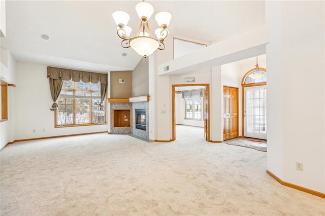 unfurnished living room with a fireplace, high vaulted ceiling, carpet floors, and a chandelier