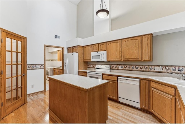 kitchen featuring white appliances, light hardwood / wood-style flooring, decorative light fixtures, and a kitchen island