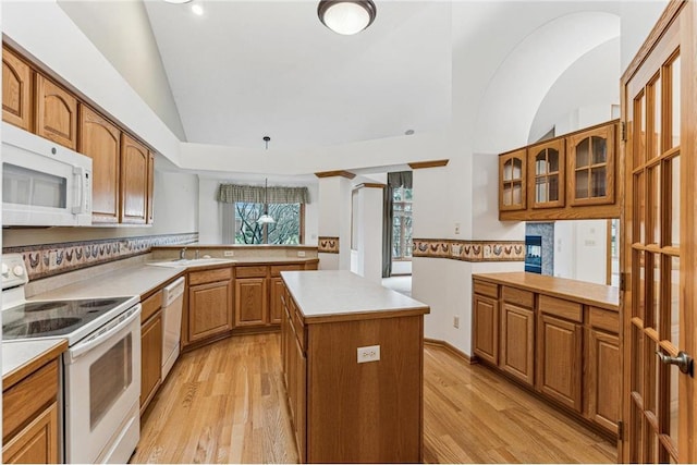 kitchen featuring white appliances, kitchen peninsula, hanging light fixtures, and a center island