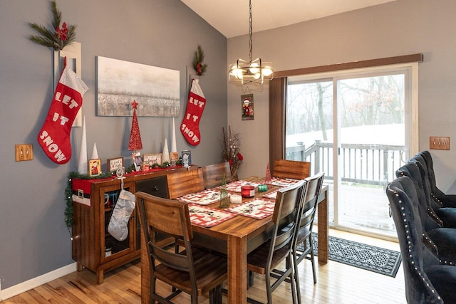 dining space with baseboards, a notable chandelier, and light wood finished floors