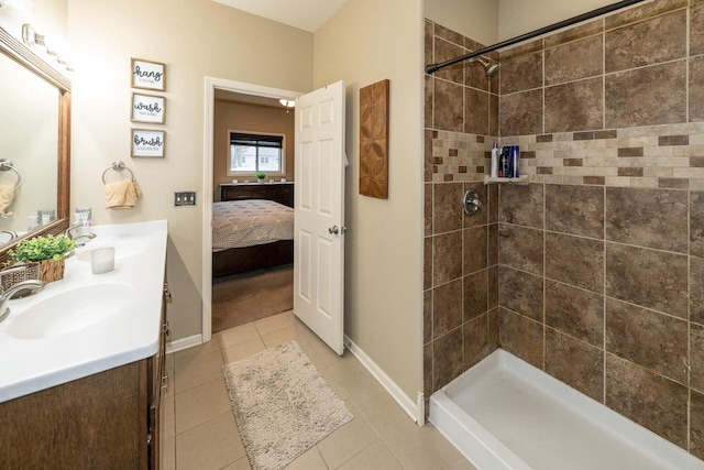 ensuite bathroom featuring tile patterned flooring, a tile shower, and a sink