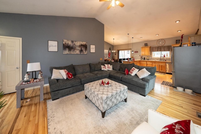 living area featuring lofted ceiling, light wood-style flooring, and a ceiling fan