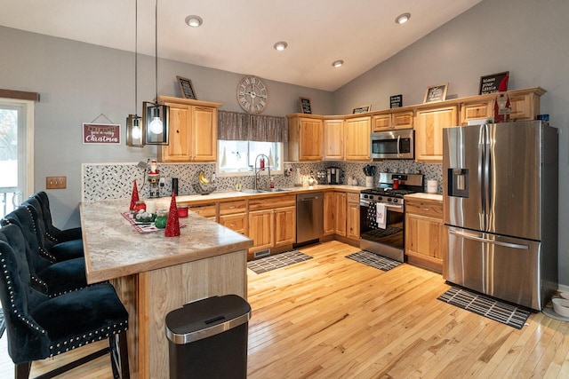 kitchen featuring a peninsula, lofted ceiling, a sink, stainless steel appliances, and light countertops