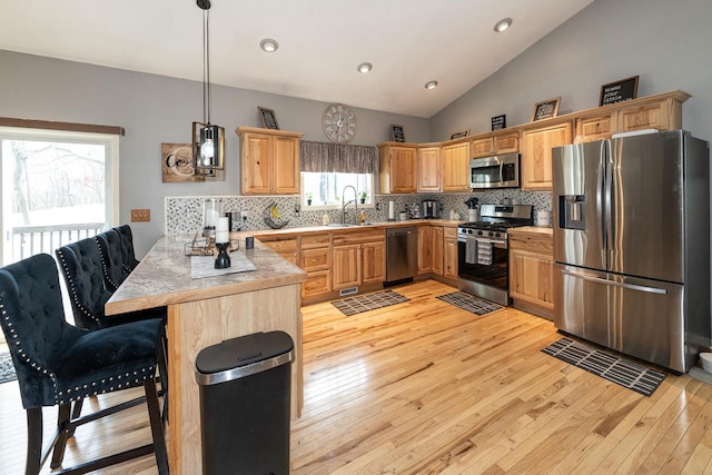 W3769 Alder Dr, Lake Geneva, WI 53147 - kitchen featuring stainless steel appliances, light wood-style flooring, a peninsula, backsplash, and lofted ceiling